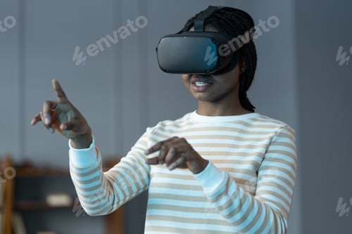 Preview: Black girl in virtual reality glasses feeling excited and amazed, touching object in virtual world