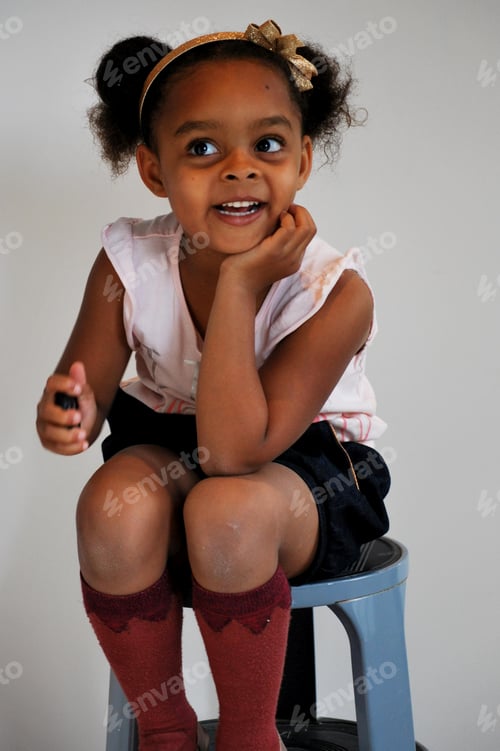 Preview: Cute little girl (black /mixed) wearing a hair bow and posing with cute knee socks - smile