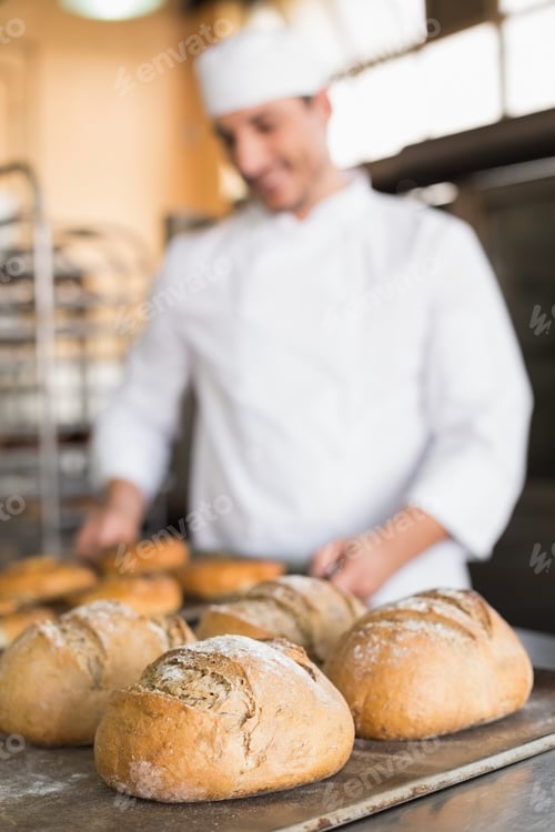 Preview: Happy baker taking out fresh bagels in the kitchen of the bakery