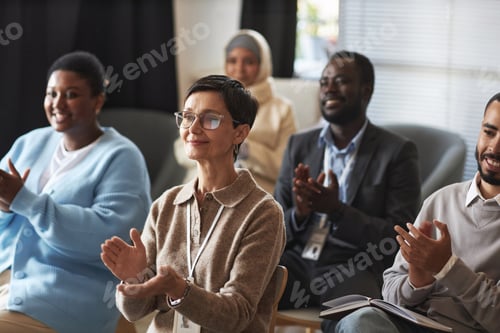 Preview: Smiling mature female manager and other employees clapping hands