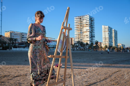 Preview: Woman Standing Next to Easel on Beach