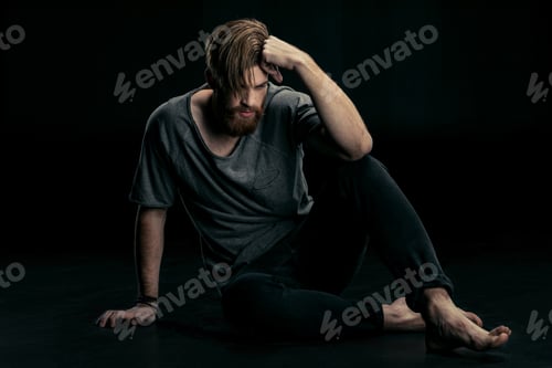 Preview: stylish handsome man sitting on floor on black