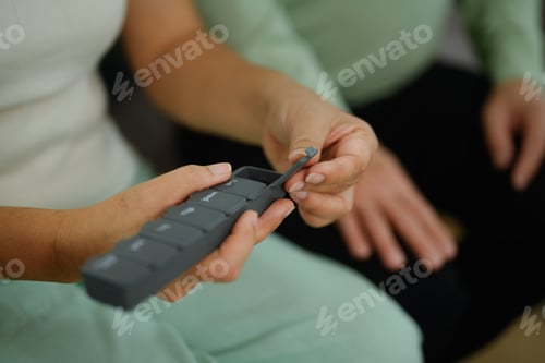 Preview: Closeup mature woman taking medicine from pill organizer box. Health care concept