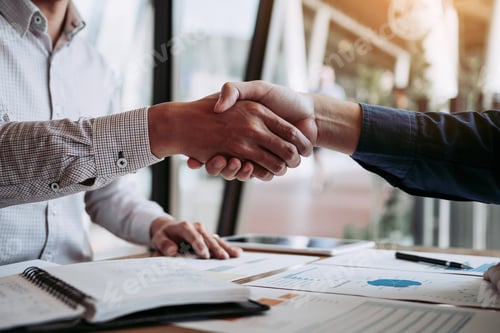 Preview: Entrepreneurs collaboration deal shaking hands in a modern office and financial paper graph on desk.