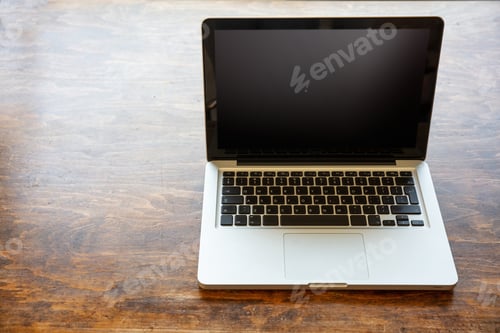 Preview: Laptop with black blank screen on a wooden desk , home office concept, copy space