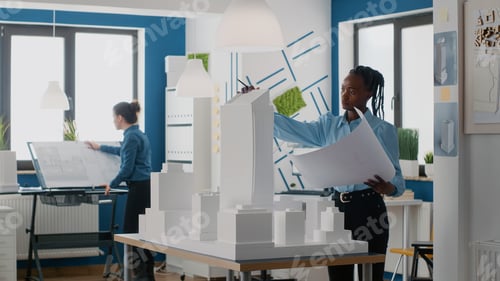 Preview: Engineer holding blueprints plan and analyzing building model for architecture work