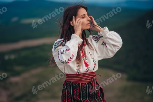 Preview: Atractive woman in traditional romanian costume on mountain green blurred background