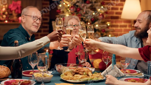 Preview: Festive diverse family members enjoying Christmas dinner at home while drinking champagne