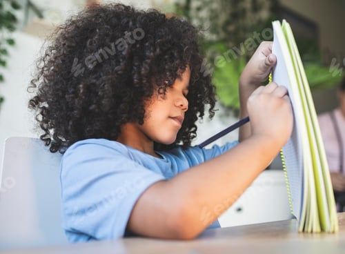 Preview: little boy doing homework at home with his notebook