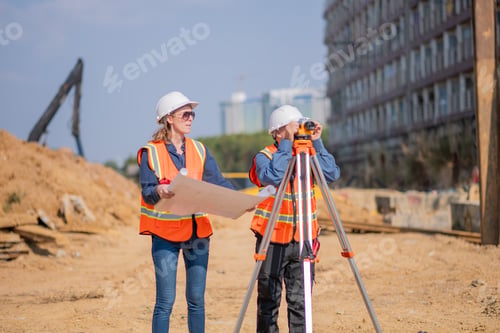 Preview: Construction surveyor or engineer working construction site blueprint and laptop for inspection deta