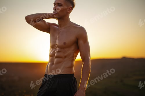 Preview: Crop strong shirtless man touching neck and looking away during training at sundown