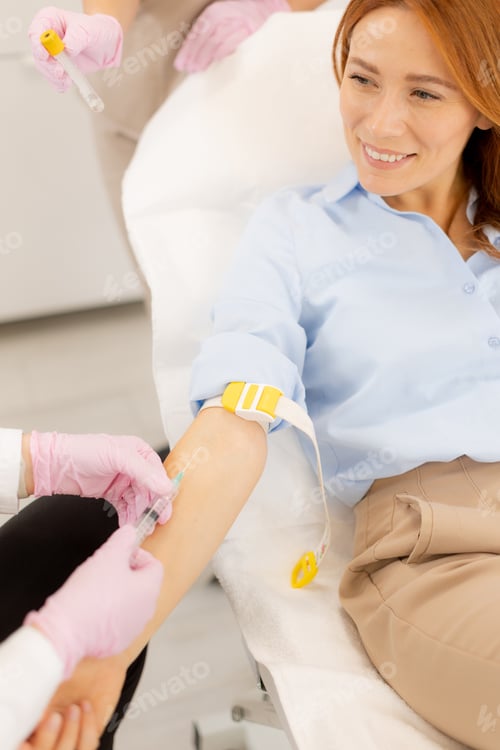 Preview: Woman smiling as a healthcare professional prepares to draw blood in a modern clinic environment