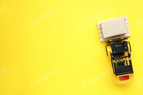 Preview: Toy forklift with wooden pallet and box on yellow background, top view. Space or text