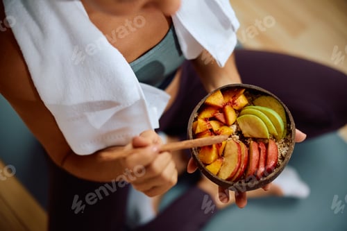 Preview: Close up of woman eating fruit salad after exercising.