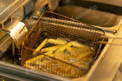 Preview: close-up in professional kitchen frying French fries in oil in a deep fryer