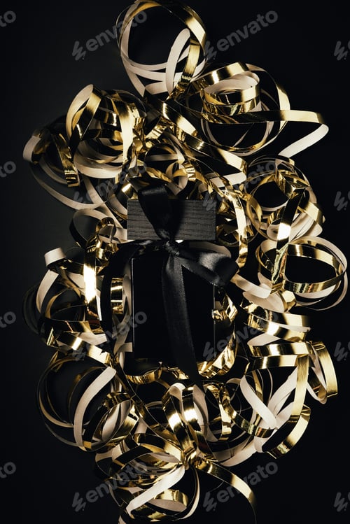 Preview: close-up view of black perfume bottle with bow and shiny golden ribbons on black