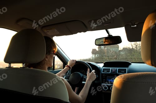 Preview: Close up view of a woman driver holding steering wheel driving a car at sunset