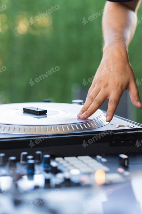Preview: Hand of a DJ touching the turntable of the mixing console