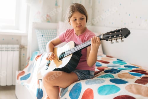 Preview: Girl Practicing Guitar While Sitting on Bed