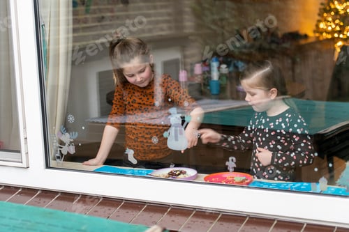 Preview: Young sisters putting a snowman on their window to celebrate Christmas