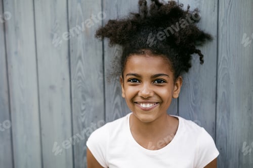 Preview: Portrait of a funny smiling girl, standing at wall outdoors