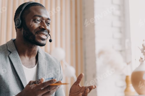 Preview: Handsome african american businessman in headset speaking by video call in office