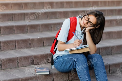 Preview: A thoughtful girl student is sitting on the stairs near the university