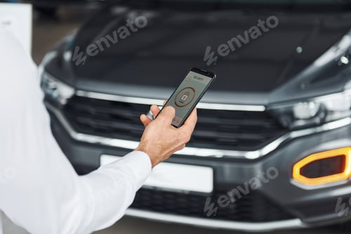 Preview: Close up view of man's hand that holds phone with labels and icons. Conception of remote control