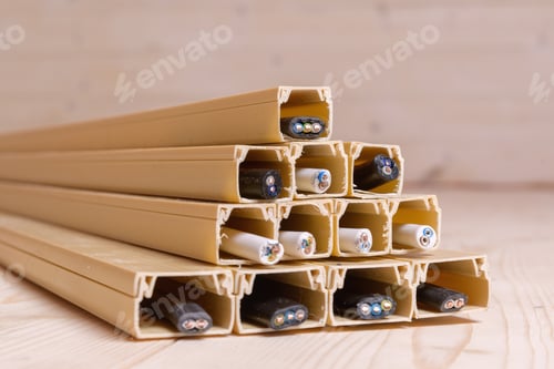 Preview: Plastic cable channels filled with various electric wires form a pyramid on a wooden floor
