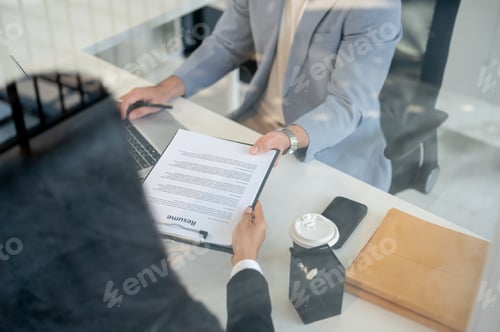 Preview: A close-up of a female candidate handing her resume to a CEO during an interview in the office.