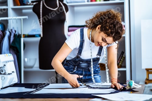Preview: The beautiful tailor sews a dress on the table