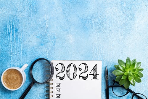 Preview: New year resolutions 2024 on desk. 2024 goals list with notebook, coffee cup, plant on blue table