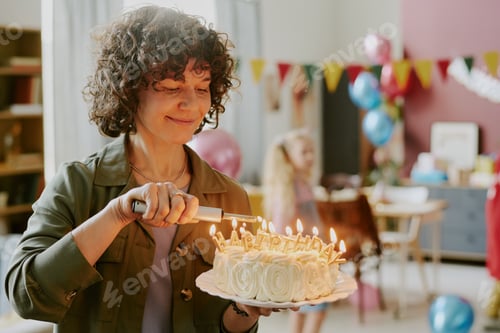 Preview: Middle Aged Caucasian Woman Lighting Birthday Cake Candles during Celebration