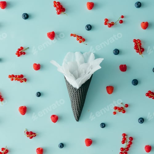 Preview: White flower in ice cream cone with forest fruit pattern. Flat lay. Summer concept.