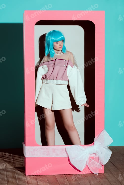 Preview: attractive girl in fashionable clothes and blue wig posing in decorative box with bow