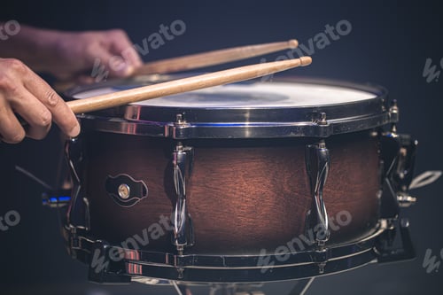 Preview: Drummer playing drum sticks on a snare drum on black background.