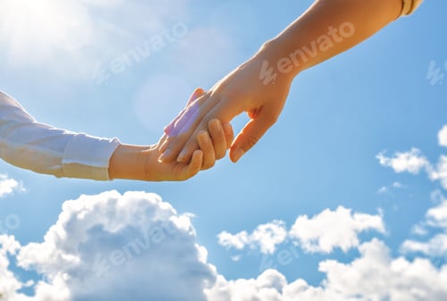 Preview: Hands of adult and child on blue sky background