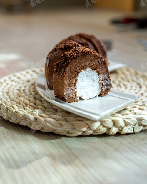 Preview: Chocolate roll with fresh cream on a white plate and wooden background