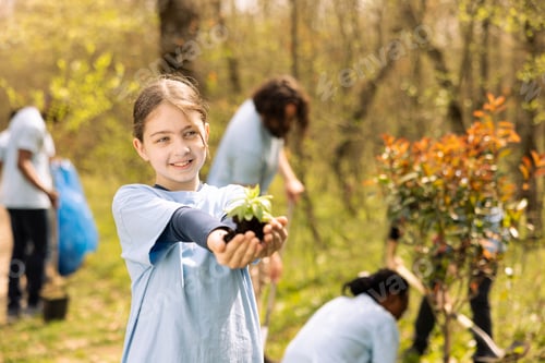 Preview: Youngster advocating for conservation of forest ecosystems by holding seedling