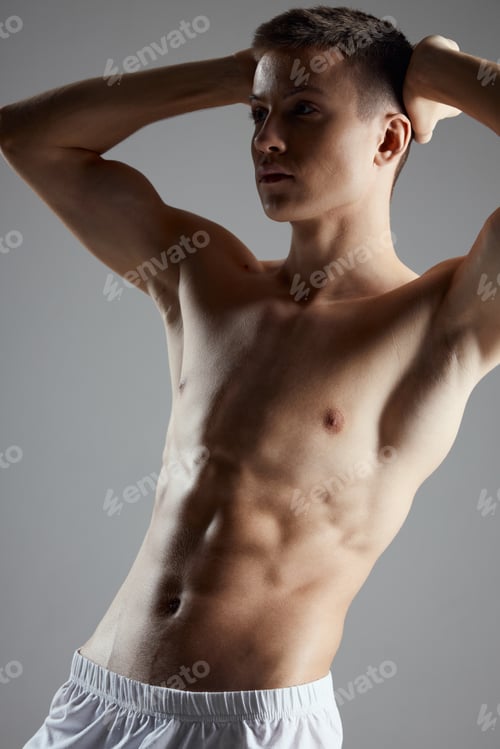 Preview: bodybuilder with a pumped-up torso holding his hands behind his head on a gray background cropped
