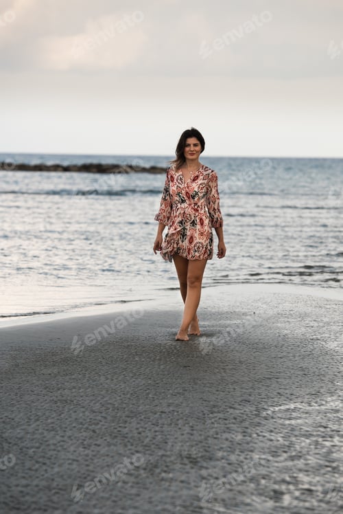 Preview: Young woman walking barefoor on a sandy beach
