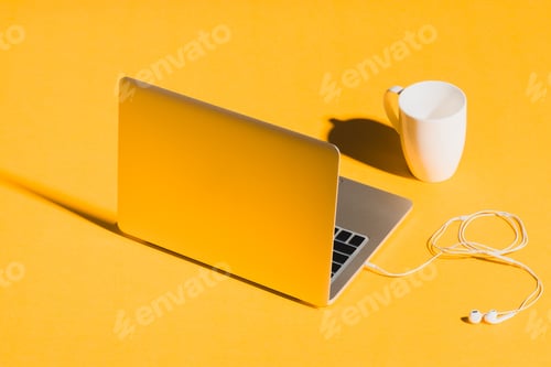 Preview: laptop with earphones and coffee cup on yellow background