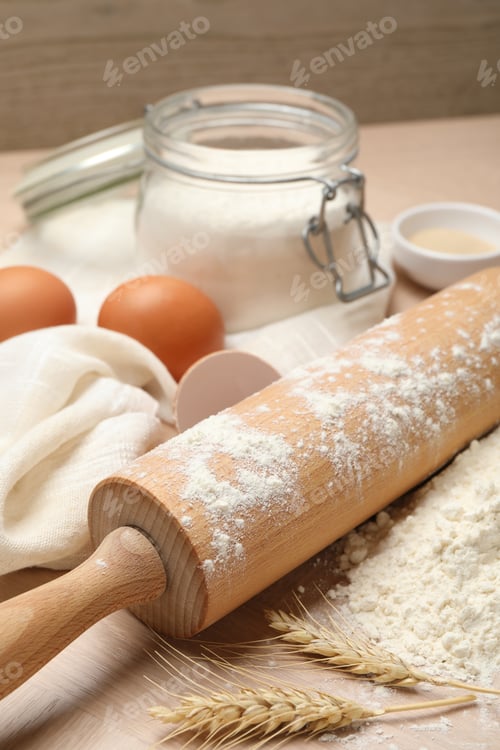 Preview: Rolling pin, flour and eggs on wooden table, closeup