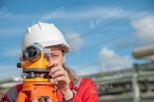 Preview: Woman engineer using theodolite outdoors