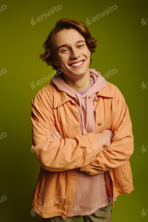 Preview: Fashionable young man displays confident style against a vibrant green background