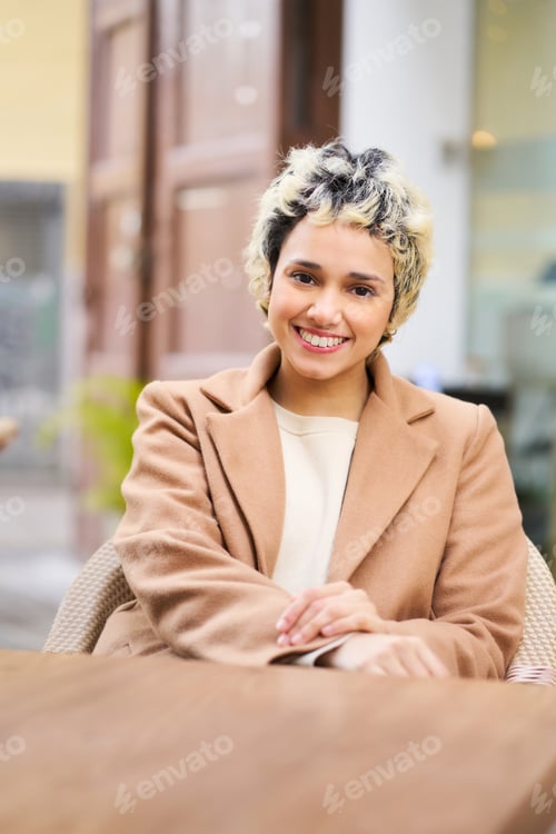 Preview: Smiling young woman sitting at outdoor cafe