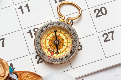 Preview: travel and vacation concept, compass on planner calendar
