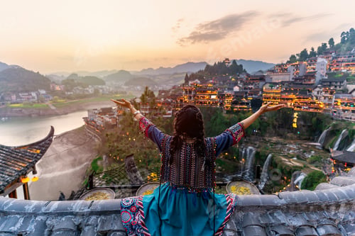 Preview: Young female tourist in traditional dress looking at the beautiful landscape at the Furong old Town