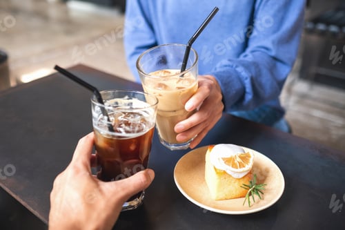 Preview: A couple people clinking coffee glasses together with lemon cake on the table in cafe