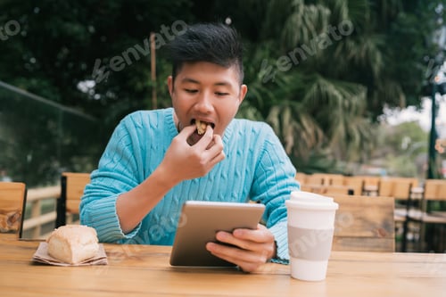 Preview: Asian man using his digital tablet.